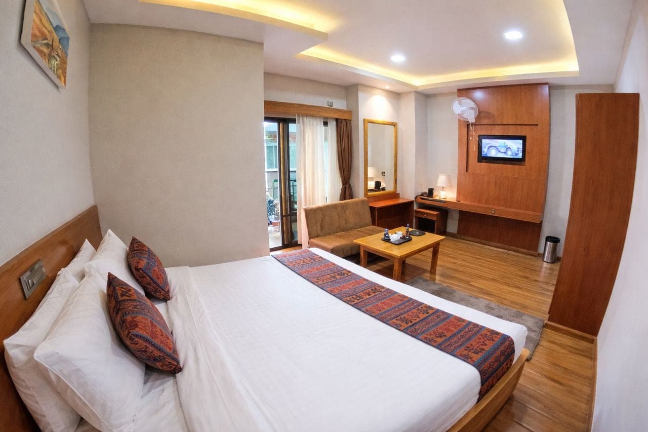 Superior Deluxe Single room with a large bed, Bhutanese textile runner, two-seater sofa, coffee table and TV unit