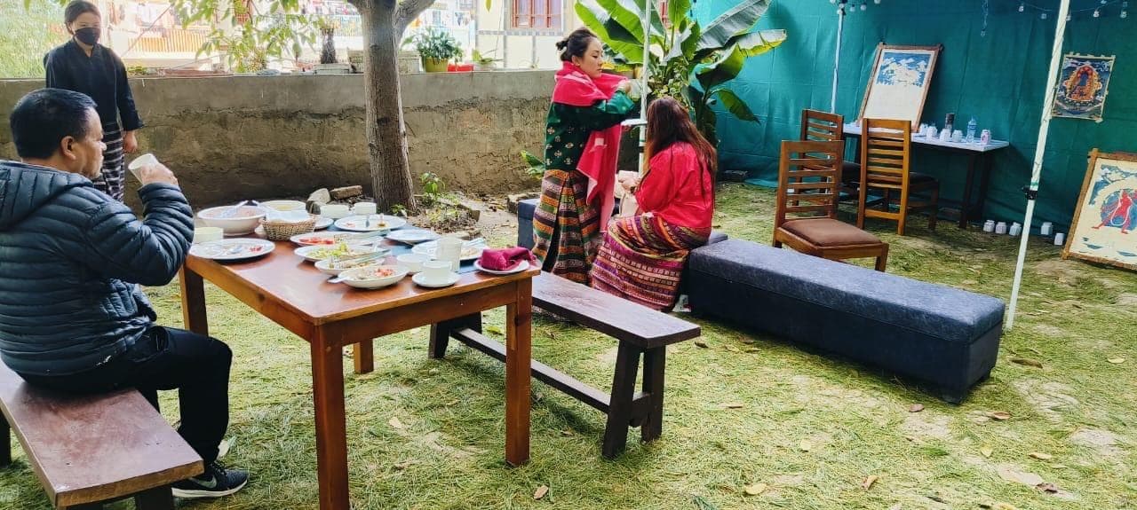 Guests dining at a wooden table on the backyard lawn