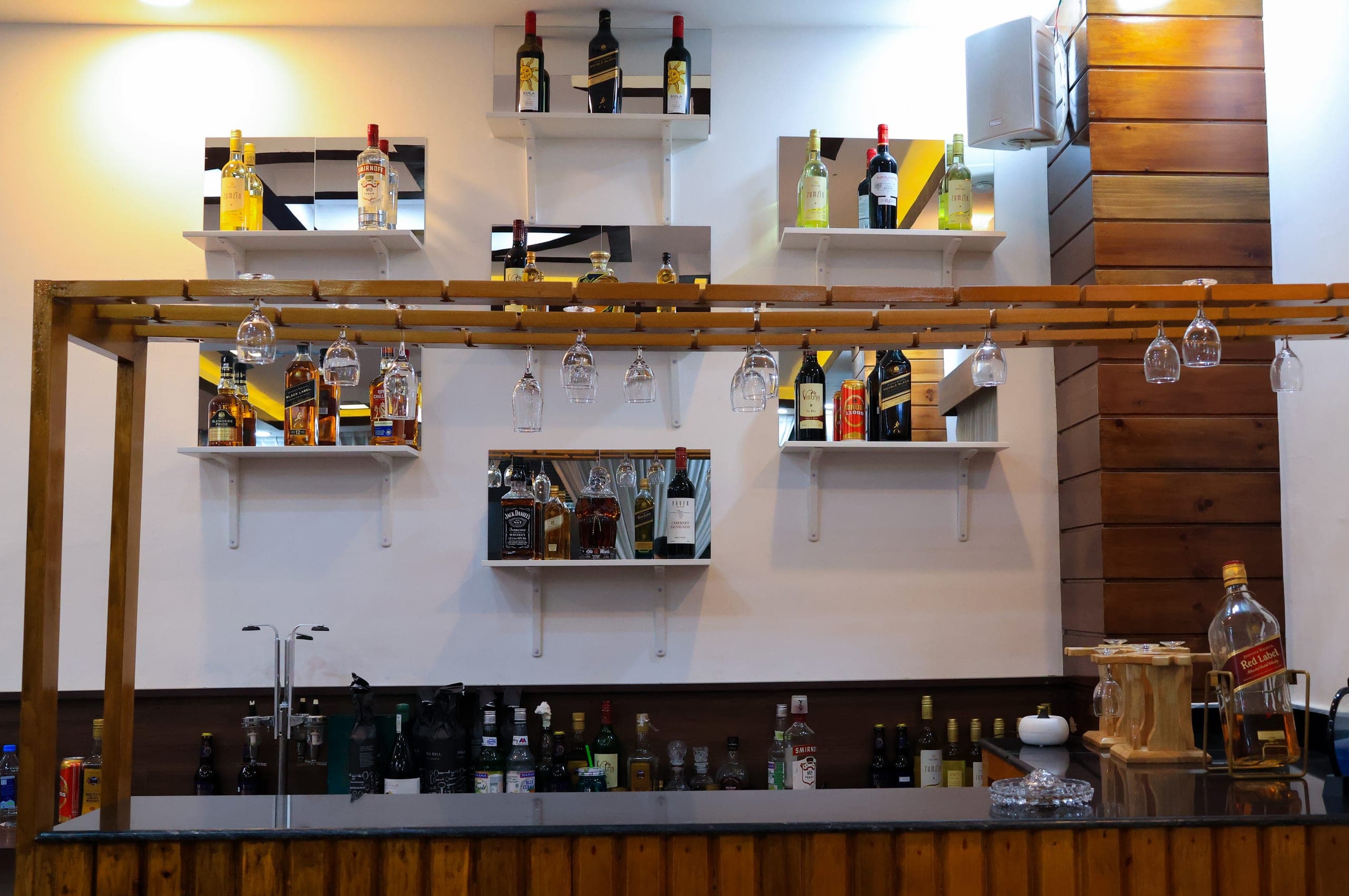 The hotel bar with a wooden frame, hanging glasses and shelves of bottles